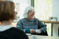 Quelle: unsplash.com/@agecymru, https://unsplash.com/de/fotos/eine-frau-die-mit-einer-tasse-kaffee-an-einem-tisch-sitzt-vDn_nPp5Xhc Frauen sitzen beim Kirchencafé zusammen